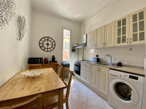 une cuisine avec une table et une machine à laver dans l'établissement Appartement Auber, à Nice