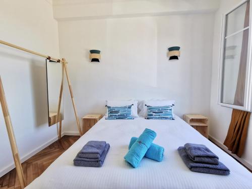 a bedroom with a white bed with blue towels on it at LE FOCH by Booking Guys in Villefranche-sur-Mer