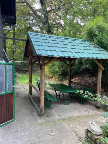a picnic shelter with a green roof and benches at Čarobna koliba M&M in Čortanovci