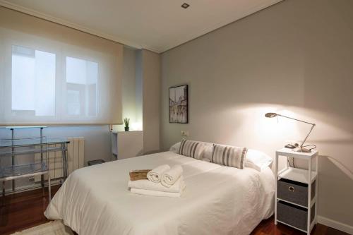 Un dormitorio con una cama blanca con toallas. en Paraguay 14, en Vigo