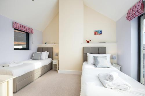 two beds in a room with white walls at Luxury property with spa access on a nature reserve Hambury Cottage BV22 in Warmwell