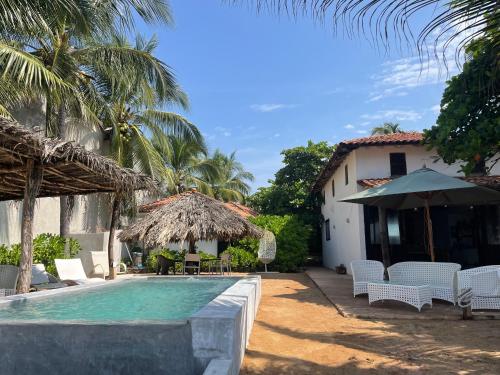 a resort with a swimming pool and chairs and a building at Quinta Feliz Troncones in Troncones