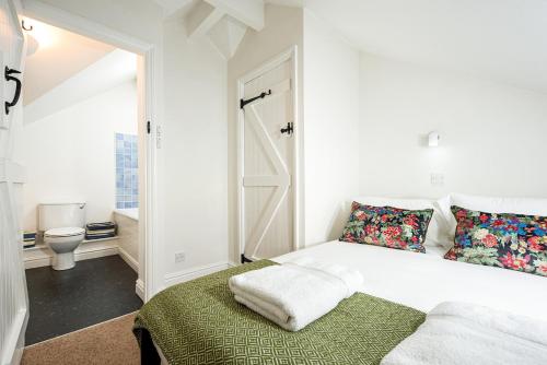 a white bedroom with a bed and a bathroom at Lakeside property with spa access on a nature reserve Ruby Cottage MV04 in Somerford Keynes