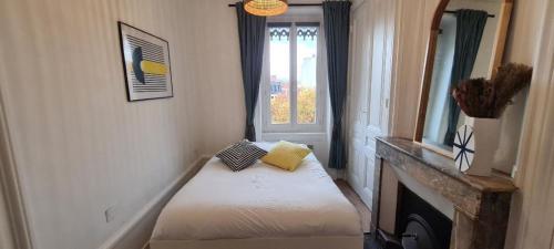 Zimmer mit einem Bett, einem Kamin und einem Fenster in der Unterkunft Appartement deux chambres - Garibaldi in Lyon