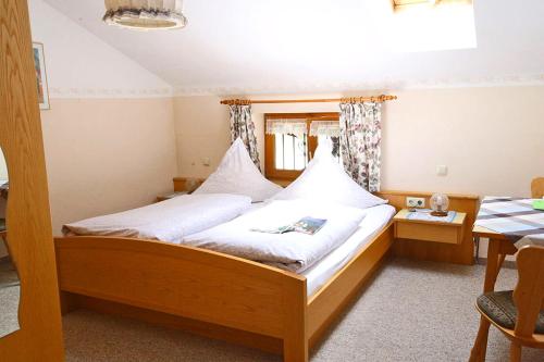 Schlafzimmer mit einem Bett mit weißer Bettwäsche und einem Tisch in der Unterkunft Bauernhof Ertlhof in Sachrang