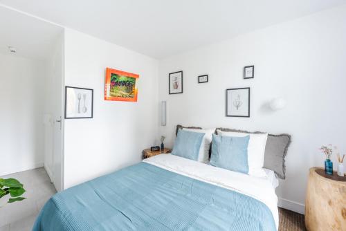 a white bedroom with a bed with blue sheets at ROOM SAUVAGE in Vincennes