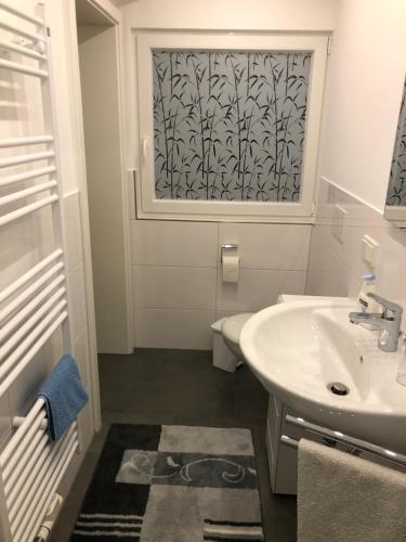 a white bathroom with a sink and a window at Ferienwohnung Wolf in Reichshof 