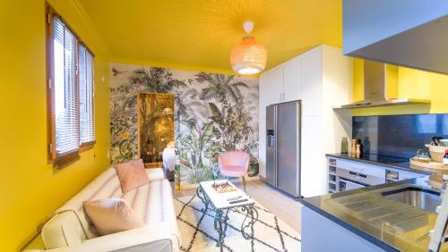 ein Wohnzimmer mit einem Sofa und eine Küche mit gelben Wänden in der Unterkunft Luxury Copacabana proche Orly et Paris avec baignoire extérieur in Draveil