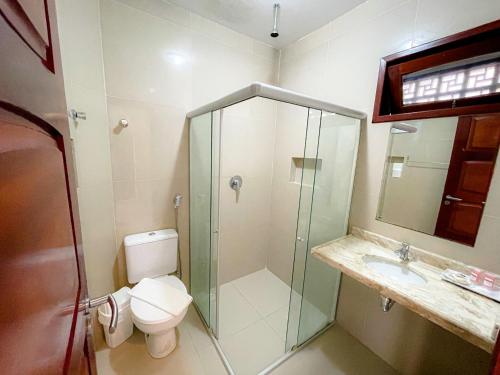 a bathroom with a toilet and a glass shower at Pousada San Giovanni in Japaratinga