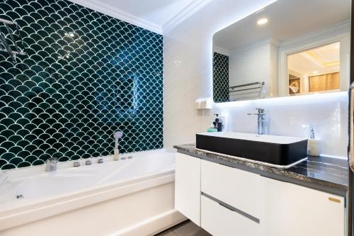 a bathroom with a white tub and a sink and a mirror at TeeUp Home - Infinity Pool Signature in Ho Chi Minh City