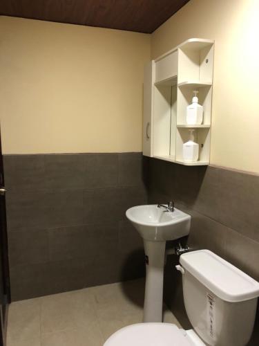 a bathroom with a white toilet and a sink at Penthouse w/rooftop terrace - volcano view in Baños