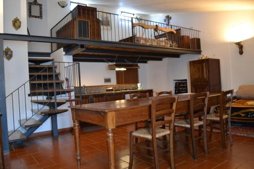 uma sala de jantar com uma mesa de madeira e uma escada em espiral em Osteria Carnivora Guest House em Gaiole in Chianti