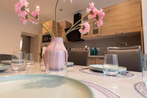 une table avec un vase avec des fleurs roses dans l'établissement Cabana & La Cascade, à Mâcon