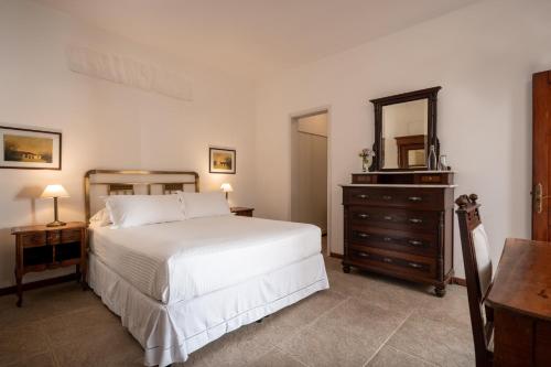 a bedroom with a bed and a dresser and a mirror at Posada Manuel Lobo in Colonia del Sacramento