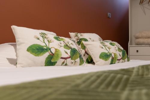 a bed with white pillows with green leaves on it at La Cascade in Mâcon