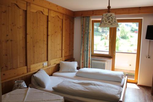 アウフファッハにあるPension Luzenbergのウッドウォールと窓が備わるドミトリールームのベッド2台分です。