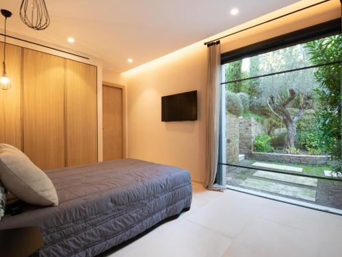 ein Schlafzimmer mit einem Bett und einem großen Fenster in der Unterkunft Villa Ghislaine in Saint-Tropez
