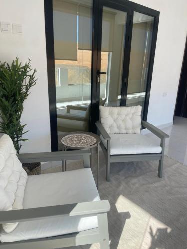 a living room with two white chairs and a mirror at Home X4 in Al Wāşil