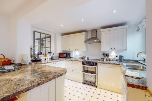 eine Küche mit weißen Schränken und Granitarbeitsflächen in der Unterkunft Stunning one bedroom apartment in Honor Oak in London