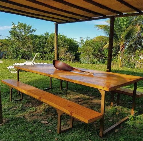 a wooden picnic table with two benches under a pavilion at Pousada Cantoria in Cumuruxatiba