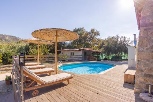 a swimming pool with two chairs and an umbrella at Villa Galateia in Dhafnés