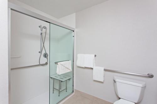 uma casa de banho com um WC e uma cabina de duche em vidro. em Holiday Inn Express Mira Mesa San Diego, an IHG Hotel em Mira Mesa