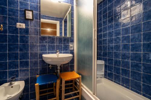 a blue tiled bathroom with a sink and a tub at Colosseo Ohana Suite in Rome