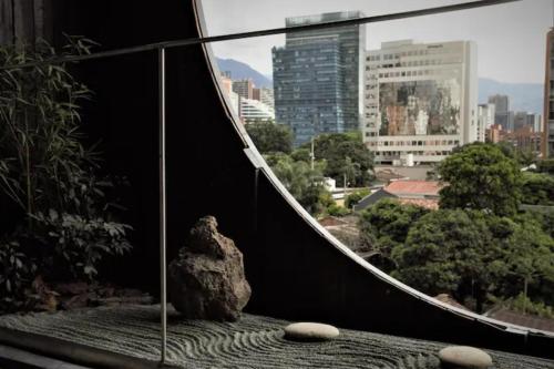 una roccia seduta in cima a un balcone con vista sulla città di Nido Sky a Medellín