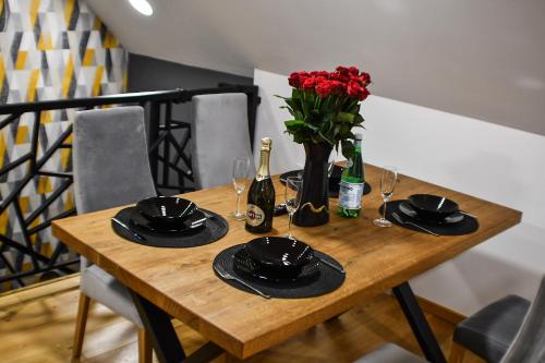 a wooden table with glasses and a vase of red roses at Apartament Orły air conditioning in Orły