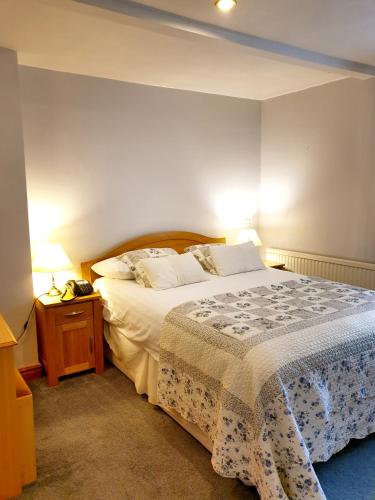 a bedroom with a large bed and a nightstand with a bed sidx sidx sidx at The Crown House Inn in Great Chesterford