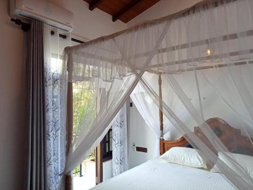 ein Schlafzimmer mit einem Himmelbett und einem Fenster in der Unterkunft Sunrise Eco Resort in Matara