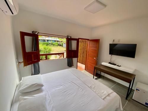 a bedroom with a bed and a desk and a television at Pousada Suzimar in Fernando de Noronha