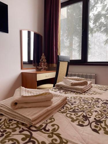 a bedroom with two beds with towels on them at HQ Apartment Flora Violet in Borovets