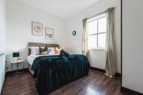 una camera da letto con un letto con una coperta verde e una finestra di Deluxe suite- 2 bed in Southampton Central a Southampton