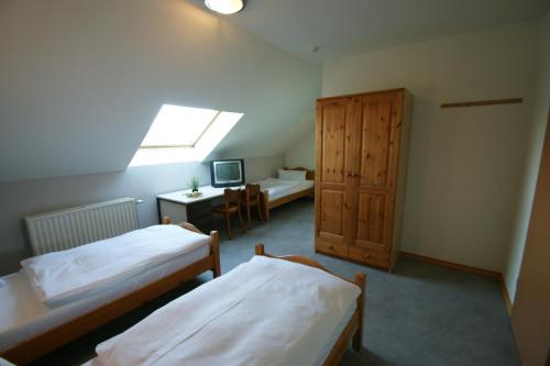 a room with two beds and a desk and a window at Hotel Restaurant Tychon AG in Eynatten