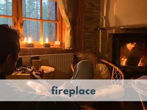 a person sitting at a table in front of a fireplace at Ferienhaus Marianna am See mit gratis Sauna, Ruderboot & WLAN in Krzywonoga