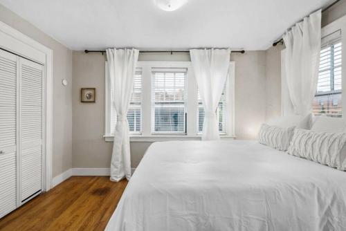 a white bedroom with a large bed and windows at Elegant and Historic Getaway Close to Everything in Oklahoma City