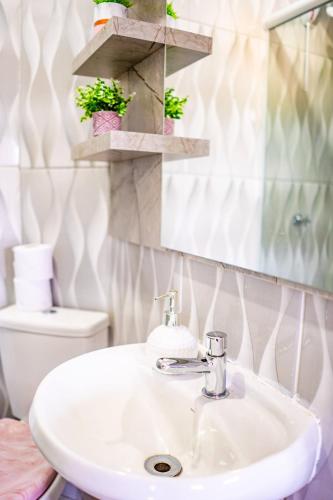 a bathroom with a sink and a mirror and a toilet at Pousada SDOIS in Imbé
