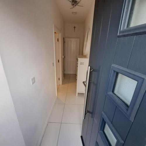a hallway with a blue door and a white tile floor at Lovely and Modern Groundfloor 1 Single Bedroom Condo with Netflix, Tea/Coffee/Biscuits in Bristol