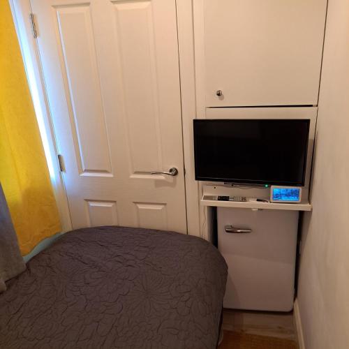 a bedroom with a bed and a flat screen tv at Lovely and Modern Groundfloor 1 Single Bedroom Condo with Netflix, Tea/Coffee/Biscuits in Bristol
