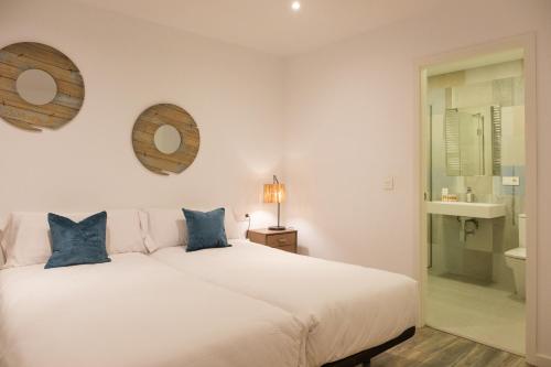 a bedroom with a white bed and a bathroom at Zafiro Flat by Serendipia Turismo in Santiago de Compostela