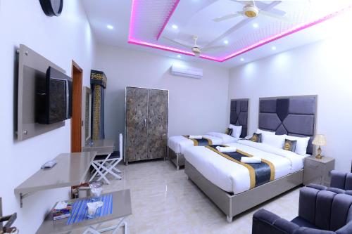 een slaapkamer met een bed, een bureau en een televisie bij Hotel Grand Lahore in Lahore
