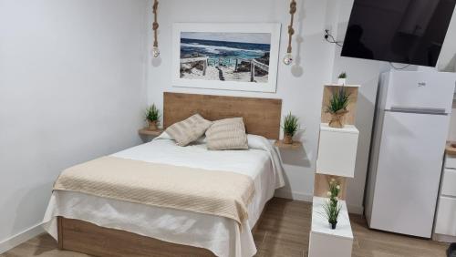 a white bedroom with a bed and a tv at Vivienda Turística Playa El Portil in El Portil