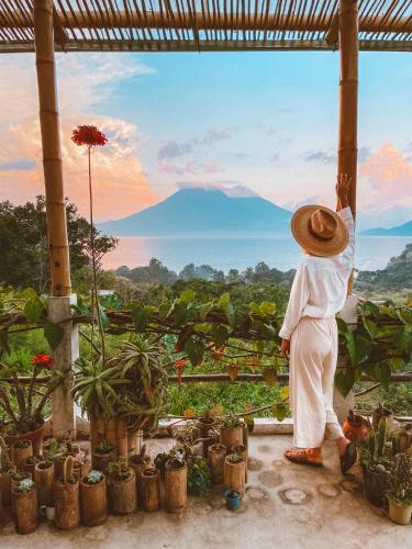 a man wearing a hat standing on a balcony looking out at a mountain at Designers Luxury Retreat with breathtaking gardens in Tzununá