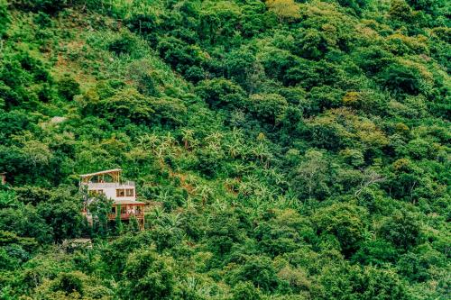 a house on the side of a hill with trees at Designers Luxury Retreat with breathtaking gardens in Tzununá