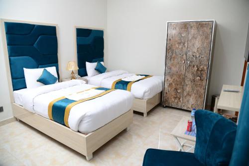 a bedroom with two beds and a chair at Hotel Grand Lahore in Lahore