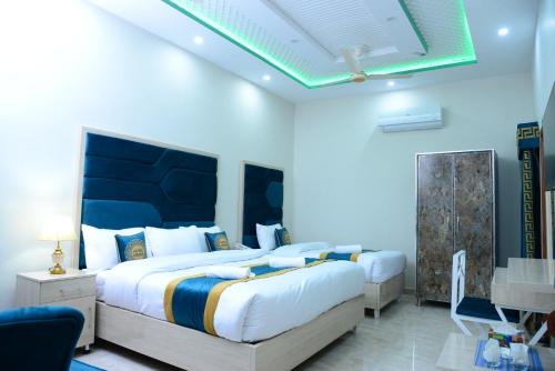 een slaapkamer met 2 bedden en een blauwe muur bij Hotel Grand Lahore in Lahore
