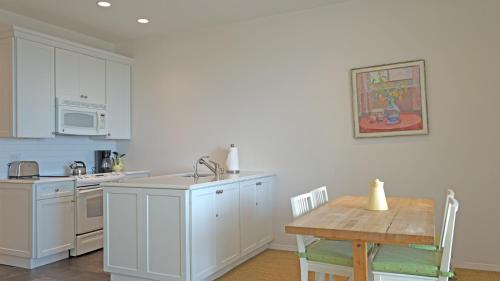 a kitchen with white cabinets and a wooden table at The Hermitage at Napeague in Amagansett