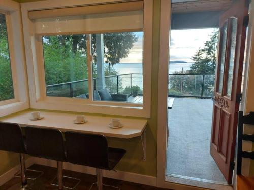 Habitación con mesa, ventana y balcón. en Relaxing 3bdr 2bth Home with Gorgeous View, en Sechelt