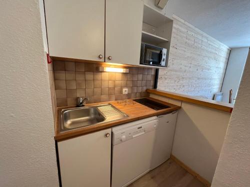 une petite cuisine avec un évier et un micro-ondes dans l'établissement Appartement cosy 4 pers - Résidence Le Pied de Pistes, au pied des remontées mécaniques - FR-1-508-23, à Lanslevillard
